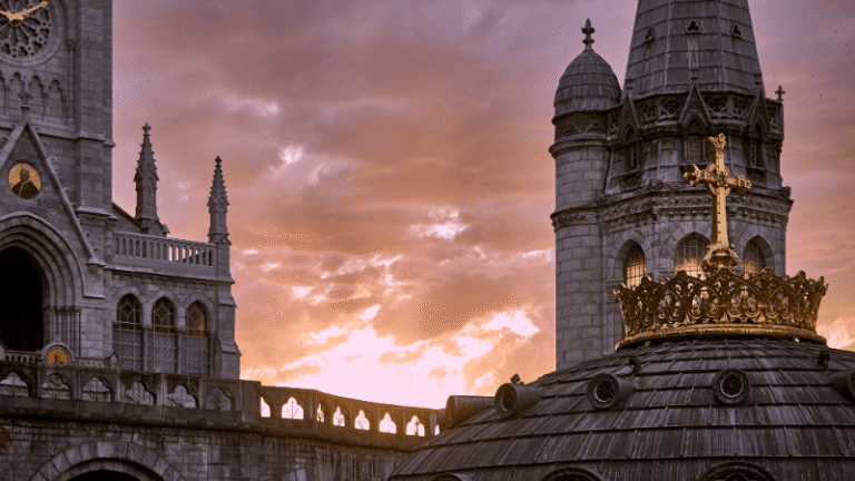 Tramonto emozionante sulla Basilica di Lourdes, con la croce dorata che brilla come simbolo di fede e spiritualità.