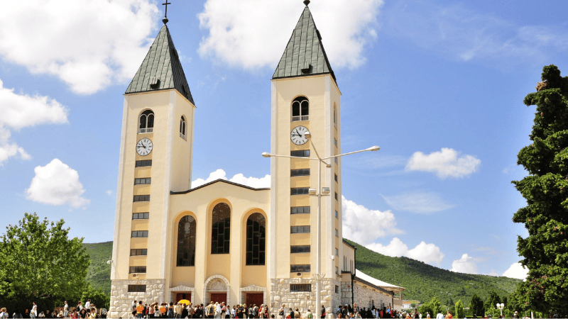 Pellegrini radunati davanti alla Chiesa di San Giacomo a Medjugorje, centro di preghiera e devozione mariana riconosciuto dal Vaticano.