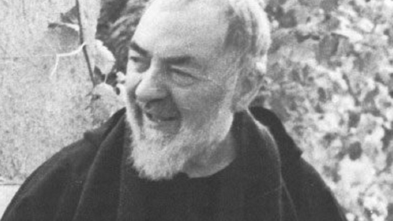 Padre Pio da Pietrelcina ritratto in un momento di serenità all’aperto, con lo sguardo sorridente e l’abito francescano.