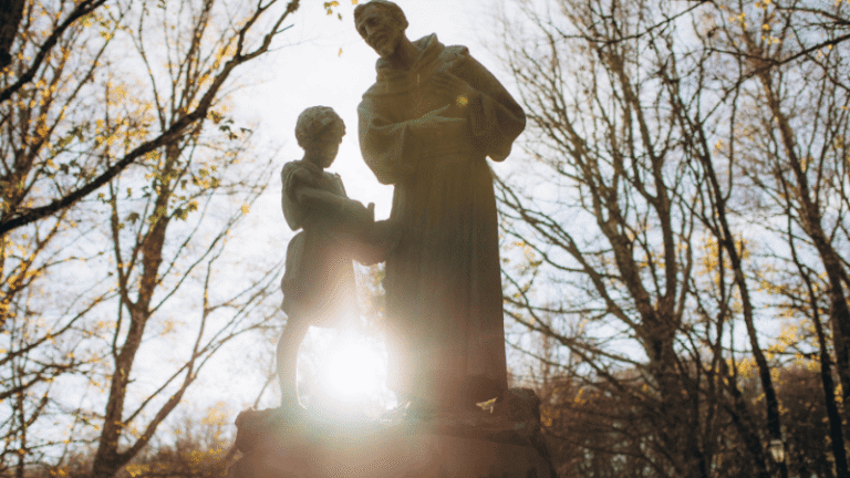 Statua di San Francesco d’Assisi con un bambino nei boschi, simbolo di fede e semplicità lungo i percorsi francescani di pellegrinaggio.