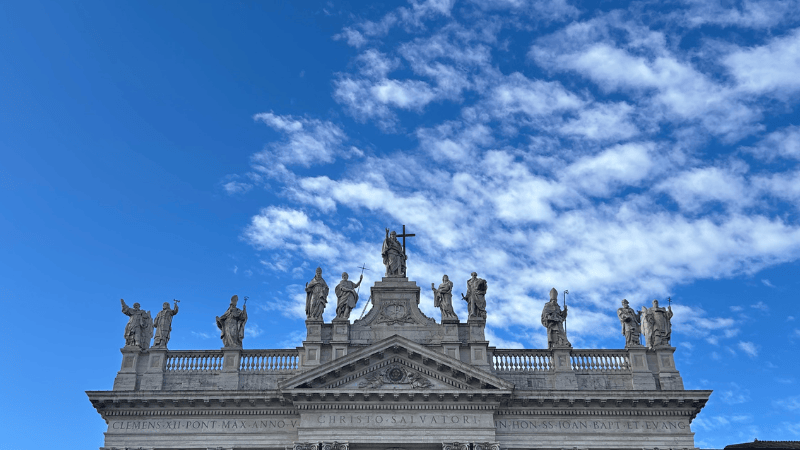 Facciata della Basilica di San Giovanni in Laterano a Roma, sormontata da statue di Cristo e dei santi, icona spirituale per i pellegrini del Giubileo