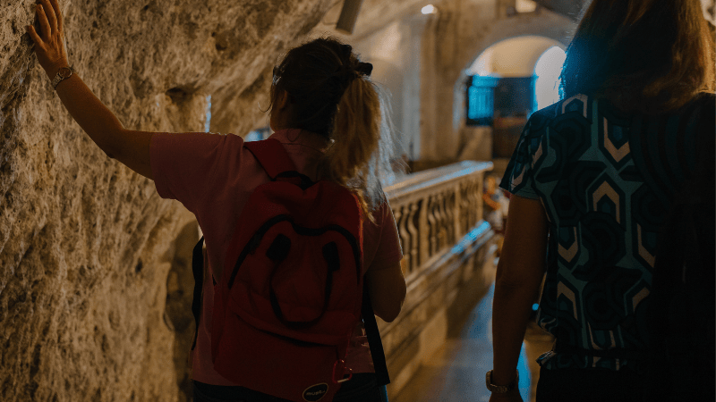 Pellegrine percorrono con devozione l’interno della grotta di San Michele Arcangelo a Monte Sant’Angelo, toccando la roccia sacra del santuario.