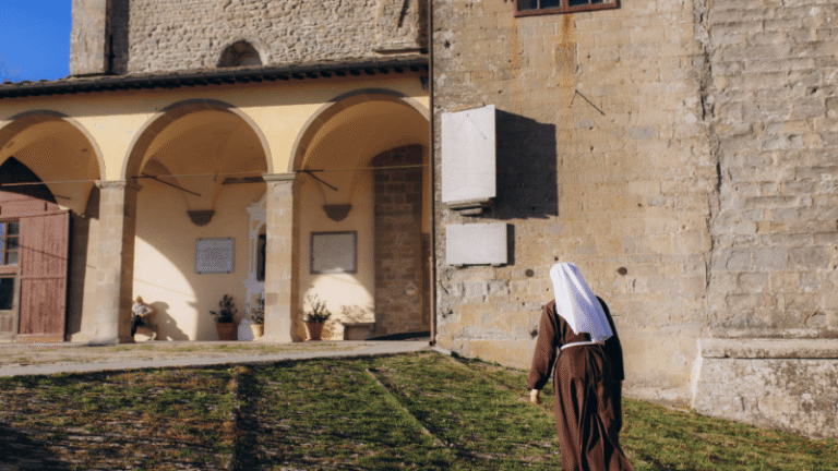 Suora francescana in preghiera al Santuario della Verna, luogo di silenzio e spiritualità legato alla memoria di San Francesco d’Assisi.