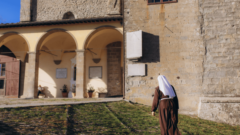 Suora francescana in preghiera al Santuario della Verna, luogo di silenzio e spiritualità legato alla memoria di San Francesco d’Assisi.