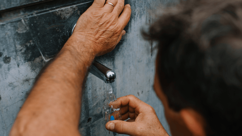Mani di un pellegrino riempiono delicatamente una bottiglietta con l'acqua benedetta delle fontane di Lourdes.