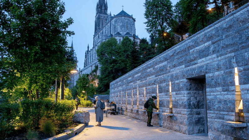 edeli raccolti in preghiera davanti alle fontane di Lourdes, luogo sacro di meditazione e guarigione spirituale.