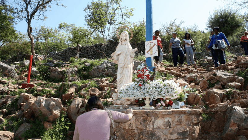 Fedeli in preghiera alla Croce Blu di Medjugorje, luogo speciale di apparizioni e raccoglimento spirituale.