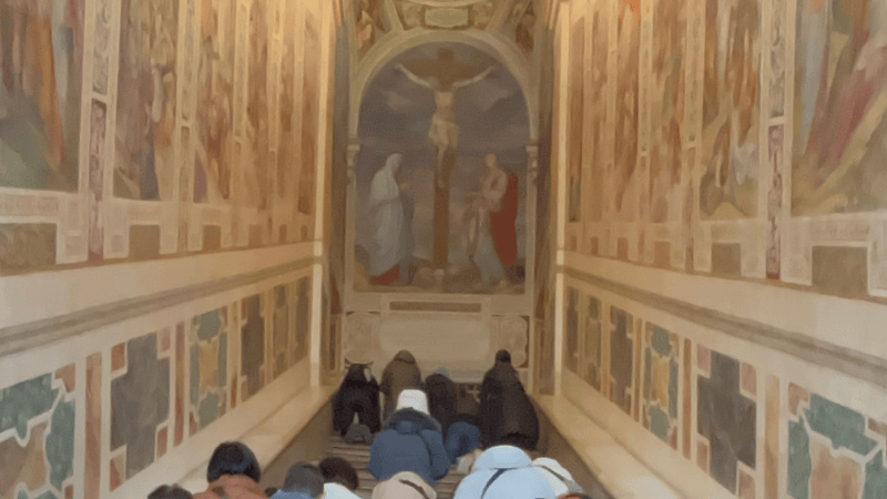 Fedeli che salgono in ginocchio la Scala Santa a Roma, in un gesto di penitenza e fede profondamente legato alla Passione di Cristo.